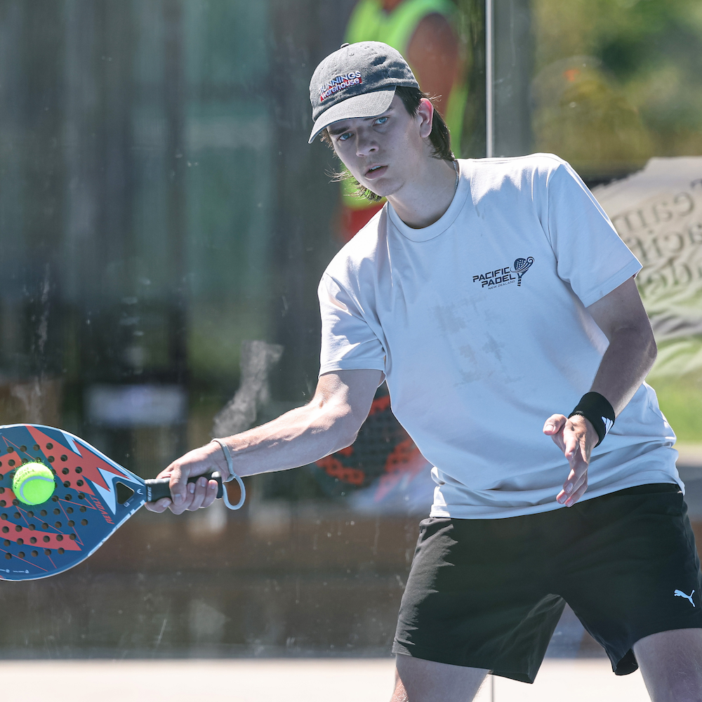 Person playing paddleball with a racket and ball, wearing a white shirt and black shorts.